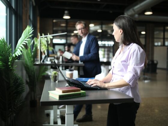 La imagen muestra a una mujer trabajando delante de un ordenador en una mesa de gran ergonomía, con altura adaptable.